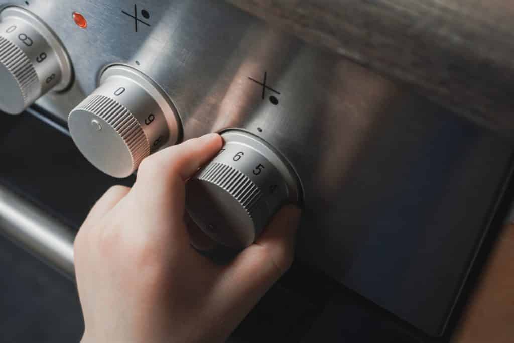 Hand Of A Child Switching On Stove Controls