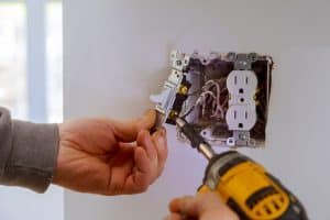 The hands of an electrician installing a power switch