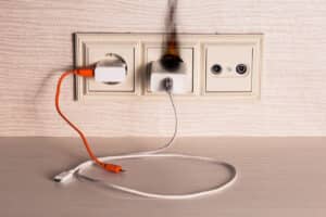 The charger of the mobile phone caught fire in the socket. Fire safety concept when using charger and wires.