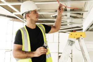 Young electrician cutting wires during his work on a construction site